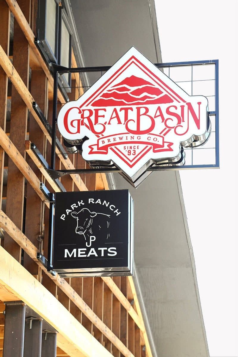 Great Basin Brewing and Park Ranch Meats hanging signs against a white sky