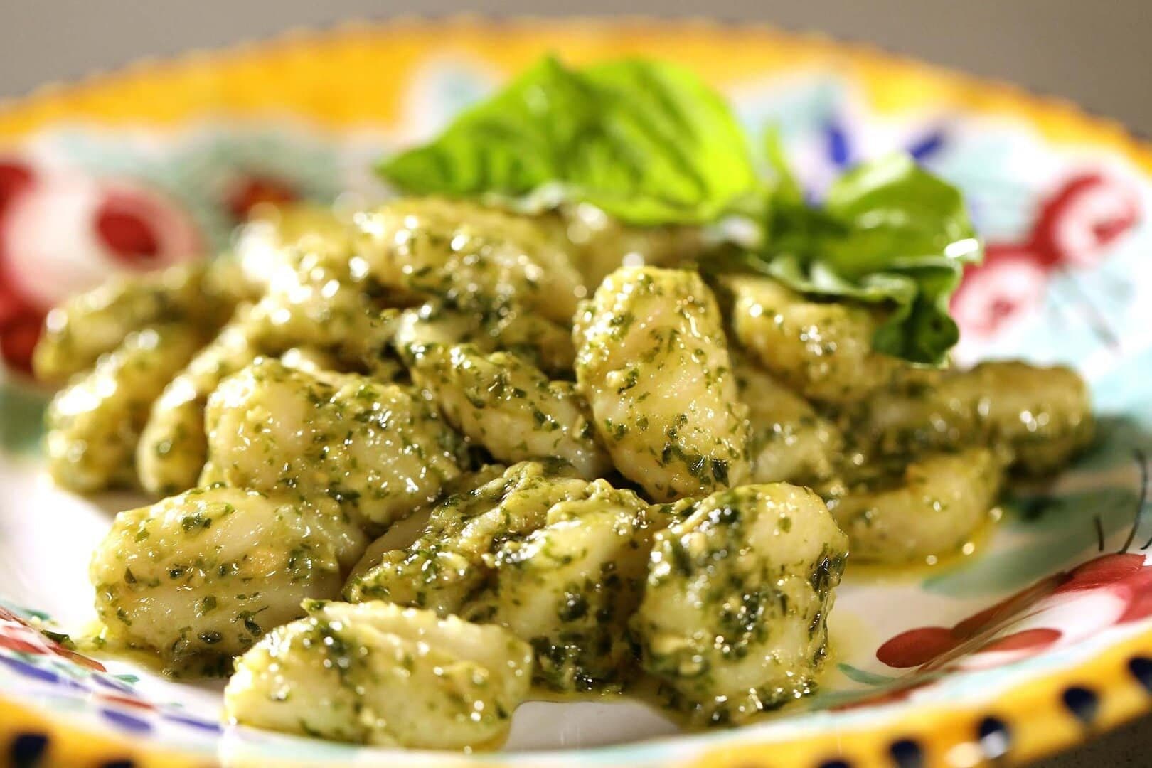 Pesto gnocchi with basil in a hand-painted ceramic bowl, bright light