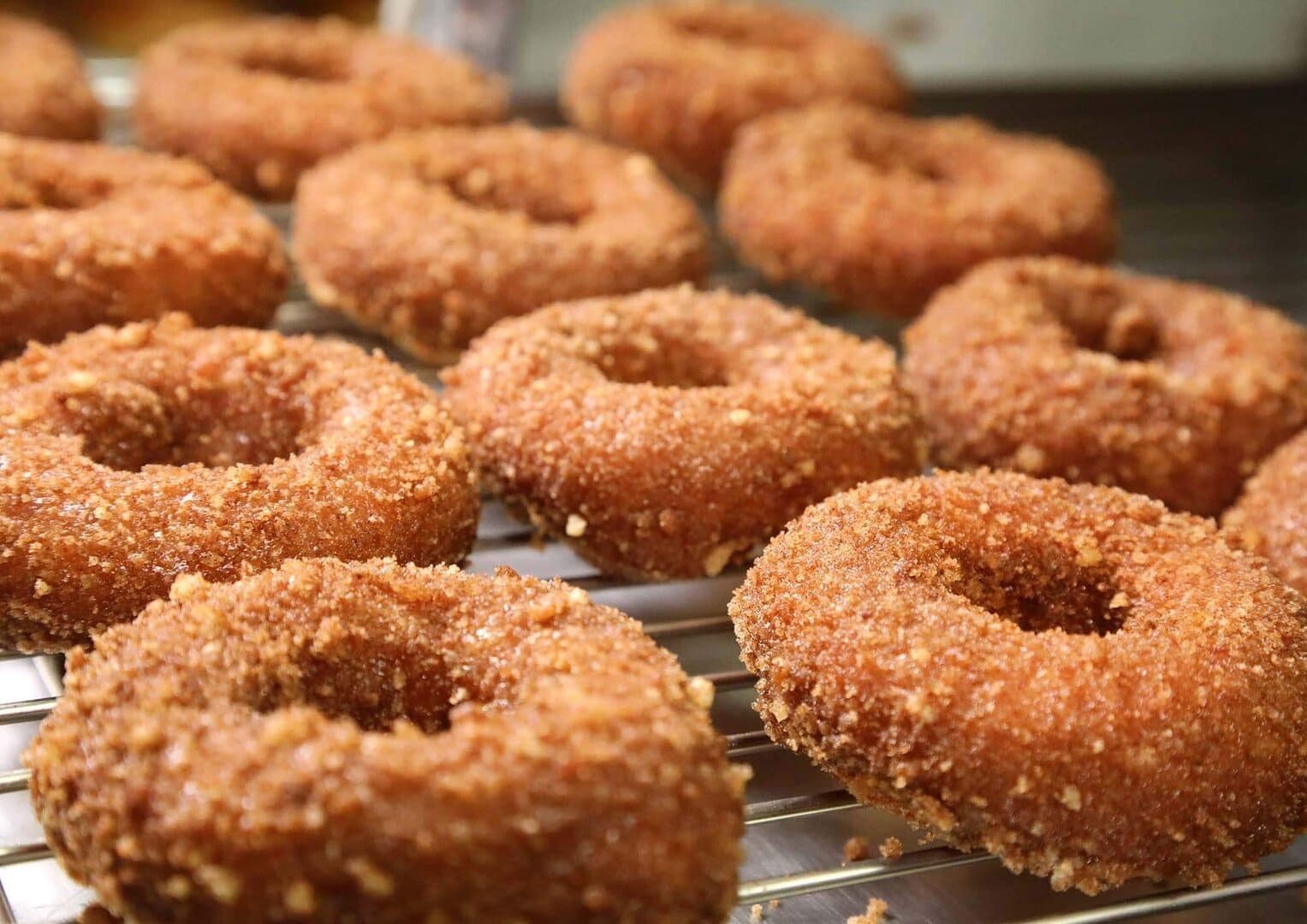 Rows of sugar-crusted pumpkin doughnuts on a wire rack, close-up