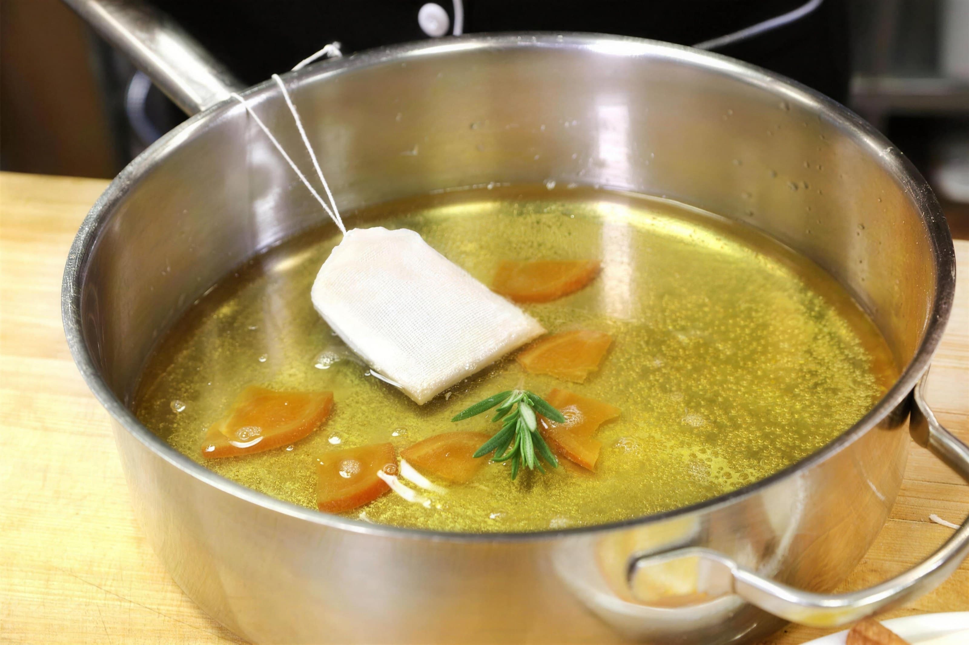 Steel pot of mulled cider with orange slices, rosemary and a spice sachet