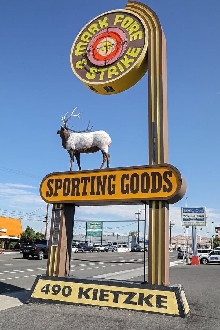 Mark Fore & Strike sporting-goods sign with elk statue against a blue sky
