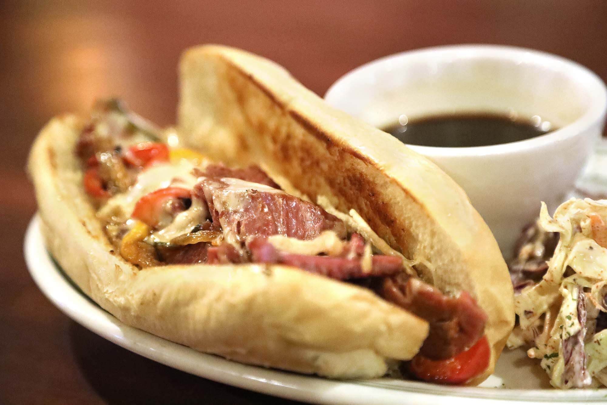 Corned beef sandwich on a roll with jus and slaw, warm close-up