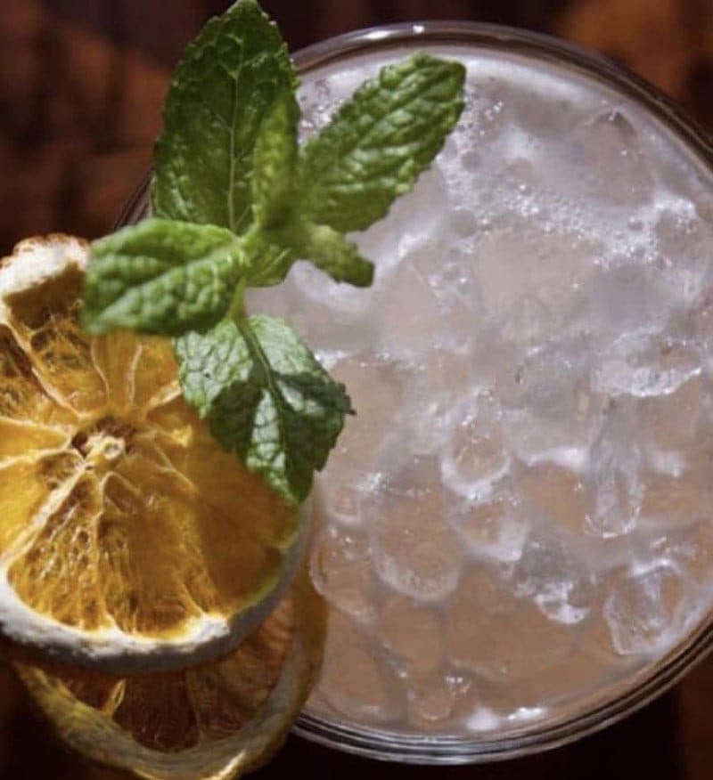 Pahranagat Punch over crushed ice with mint and dried orange, close-up, dark