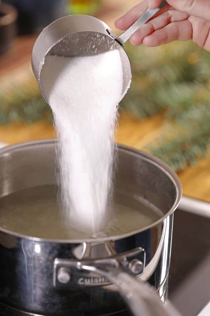 Sugar pouring into a pot of hot water, close-up, warm